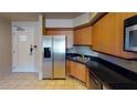 Functional kitchen area with stainless steel refrigerator, black countertops, and light wood cabinets at 211 E Flamingo Rd # 202, Las Vegas, NV 89169