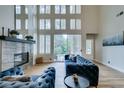 Bright living room with a fireplace, tall windows, and a blue velvet sofa overlooking a lush outdoor view at 4963 Crooked Stick Way, Las Vegas, NV 89113