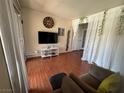 Inviting living room with hardwood floors, a large tv, and sheer curtains over french doors at 5499 Indian River Dr # 356, Las Vegas, NV 89103
