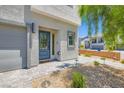 Modern home entrance with a gray front door, minimalist landscaping, and a cobblestone driveway at 5804 Gossamer Stone Ct, Las Vegas, NV 89141