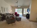 Cozy living room featuring neutral carpet, ceiling fan and sliding glass doors to backyard at 9505 Quail Ridge Dr, Las Vegas, NV 89134