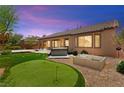Lush backyard with a putting green, patio, and relaxing hot tub at 10348 Hawks Wing St, Las Vegas, NV 89178
