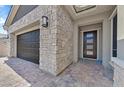 Close-up of the home's stone-accented facade, three car garage, and welcoming front entry with a decorative door mat at 2931 Raywood Ash Dr, Las Vegas, NV 89138