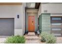 Close-up of the home's entry with a modern orange door, green accents, and a brick entry at 3358 Via Strada St, Henderson, NV 89044