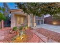 Home exterior featuring stone landscaping, a three-car garage, and mature trees in the yard at 53 Precipice Ct, Henderson, NV 89002