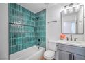 Updated bathroom features green tile in tub and shower surround, vanity, and modern fixtures at 6517 Villa Mesa Dr, Las Vegas, NV 89107