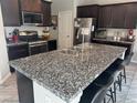 Beautiful kitchen with dark wood cabinets, stainless steel appliances, and granite countertops with seating at 6867 Dragonfly Rock St, Las Vegas, NV 89148