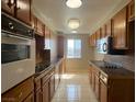 Galley kitchen offers wooden cabinets, tiled countertops, white appliances, and natural lighting at 745 N Royal Crest Cir # 157, Las Vegas, NV 89169
