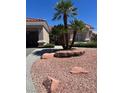 Beautiful home featuring desert landscaping with palm trees and stone accents in the front yard at 10036 Keysborough Dr, Las Vegas, NV 89134