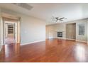 Spacious living room featuring a cozy fireplace, hardwood floors, and a ceiling fan at 11901 Luna Del Mar Ln, Las Vegas, NV 89138