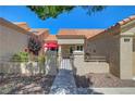 Inviting front courtyard featuring a tranquil seating area under a red umbrella and secure wrought-iron gate at 2456 Desert Butte Dr, Las Vegas, NV 89134