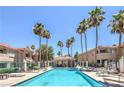 Community pool surrounded by palm trees, lounge chairs, and well-maintained buildings at 370 Manti Pl # 21, Henderson, NV 89014
