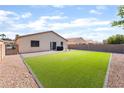 Well-maintained backyard featuring an artificial lawn, a patio, and secure fencing for privacy at 5009 Peaceful Pond Ave, Las Vegas, NV 89131