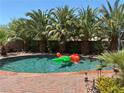 Sparkling pool surrounded by lush palm trees and a brick patio, perfect for relaxing and entertaining at 5929 Gentle Creek Ln, North Las Vegas, NV 89031