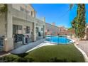 Inviting backyard featuring a refreshing pool, covered patio, and artificial turf, perfect for outdoor entertaining and relaxation at 7537 Splashing Rock Dr, Las Vegas, NV 89131