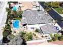 Aerial view showcases the backyard's pool, spa, and patio area, surrounded by lush landscaping and mature palm trees at 9905 Fox Springs Dr, Las Vegas, NV 89117