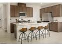 Modern kitchen with a large island, stainless steel appliances, dark cabinets, and bar stool seating at 7388 Daly Grove St, Las Vegas, NV 89113