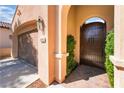 Front entrance showcases an arched gate, desert landscaping and a direct-access garage at 12276 Caminita Pl, Las Vegas, NV 89138