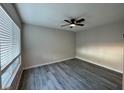 Bedroom with grey laminate wood flooring, window with blinds, and modern ceiling fan at 7144 Forest Vista St, Las Vegas, NV 89147