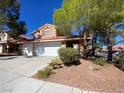 Charming two-story home with a two-car garage and desert landscaping under a clear blue sky at 7604 Cruz Bay Ct, Las Vegas, NV 89128