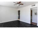Spacious living room with dark-stained wood floors, a ceiling fan, and bright white walls at 2616 Spear St, North Las Vegas, NV 89030
