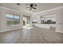 Open-concept living room featuring tile floors, a ceiling fan, and a seamless transition to the adjacent kitchen with white cabinetry at 37 Stonemark Dr, Henderson, NV 89052
