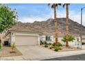 Single-story home features a two car garage, desert landscaping, tiled roof, and a mountain backdrop at 703 Jane Eyre Pl, Henderson, NV 89002