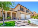 View of a beige two-story home with a well-manicured lawn, neutral accents and a double garage at 7619 Comanche Canyon Ave, Las Vegas, NV 89113