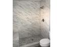 Updated shower with marbled tiles, a built-in seat, and river rock flooring at 8484 Montana Stream Ave, Las Vegas, NV 89113