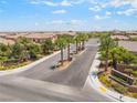 Welcoming gated community entrance with lush landscaping and palm trees under a blue sky at 9635 Ramon Valley Ave, Las Vegas, NV 89149