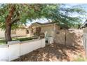 View of a beige home featuring a gated entrance, tree, and partial front yard at 1723 Candice St, Las Vegas, NV 89156