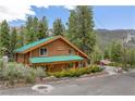 Charming log cabin-style home with a green roof, nestled in a wooded area with mountain views at 401 Alpine Way, Mount Charleston, NV 89124