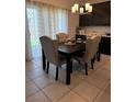 Dining room with a chandelier, a dark table with four beige upholstered chairs, and tile flooring at 1618 Dakota Group Ave, North Las Vegas, NV 89084