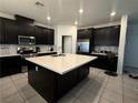 Spacious kitchen with an island, dark cabinets, stainless steel appliances, and tiled backsplash at 1618 Dakota Group Ave, North Las Vegas, NV 89084