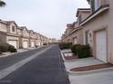 Wide community street showcasing multiple townhomes with garages and well-kept landscaping at 59 Belle Maison Ave, Las Vegas, NV 89123