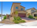 Tan two-story home featuring a two-car garage, surrounded by desert landscaping for a low-maintenance yard at 7730 Moore Creek Ln, North Las Vegas, NV 89084