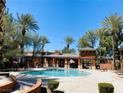 Community pool surrounded by palm trees and a shaded pergola area for relaxing and socializing at 908 Duckhorn Ct # 102, Las Vegas, NV 89144