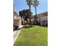Exterior view of condos with grass yard and small trees in a residential neighborhood at 925 Falconhead Ln # 102, Las Vegas, NV 89128