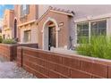 Charming townhome entrance with dark door and brick-style privacy wall amidst lush greenery at 10013 Sable Point St, Las Vegas, NV 89178