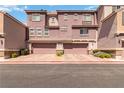 Townhome's exterior showcases a warm, mauve hue with complementary stone accents, highlighting a welcoming garage entry at 10013 Sable Point St, Las Vegas, NV 89178