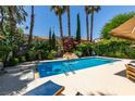Gorgeous backyard pool area featuring lush landscaping, including palm trees, and comfortable lounge chairs at 5133 Southern Hills Ln, Las Vegas, NV 89113
