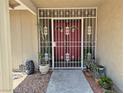 Home's decorative security gate protecting red double doors with potted plants at 7104 Carrondale Way, Las Vegas, NV 89128