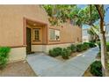 Close up of townhouse entrance featuring a covered entry, small front window and green shrubbery at 9115 Canoga Canyon Ct # 103, Las Vegas, NV 89149