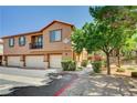 Charming exterior view of tan townhouse with a small balcony and green shrubbery at 9115 Canoga Canyon Ct # 103, Las Vegas, NV 89149