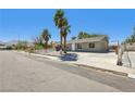 Full street view of a desert landscaped home with secure driveway and mature trees at 4825 Stillwater Ave, Las Vegas, NV 89110