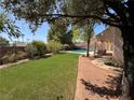 Lush backyard featuring artificial turf, a pool, a covered patio, and ample seating for relaxation at 6293 Pavestone Ln, Las Vegas, NV 89142