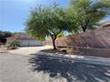 Long driveway leads to a well-maintained home with a large tree and brick wall at 6293 Pavestone Ln, Las Vegas, NV 89142