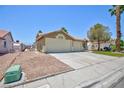 Side view of house with a two car garage, desert landscaping and a green lawn at 849 Ringwood Ln, Las Vegas, NV 89110