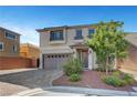 Inviting two-story home with a neutral exterior, a paved driveway and manicured landscaping at 10325 Quartz Reef Ct, Las Vegas, NV 89141