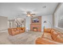 Cozy living room with leather sofas, a brick fireplace, and a ceiling fan creating a welcoming atmosphere at 10623 Kearney Mountain Ave, Las Vegas, NV 89166